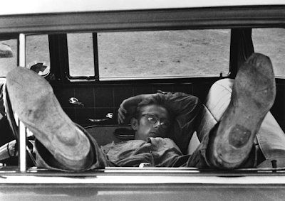 black and white photograph of James Dean's cowboy boots in car window as he naps during filming on "Giant"