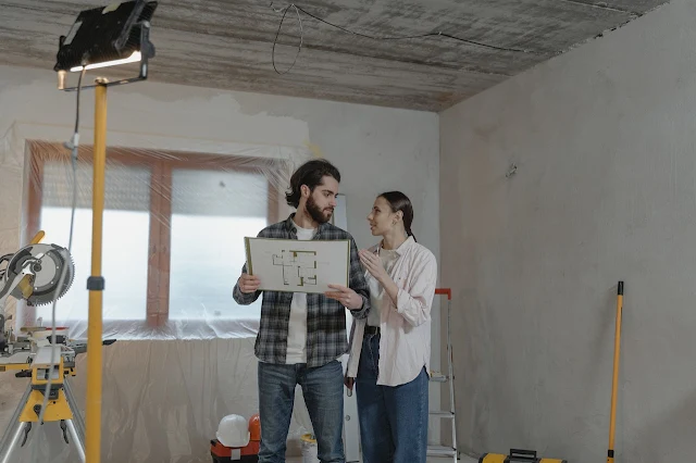 A couple in a house under construction looking at blueprints