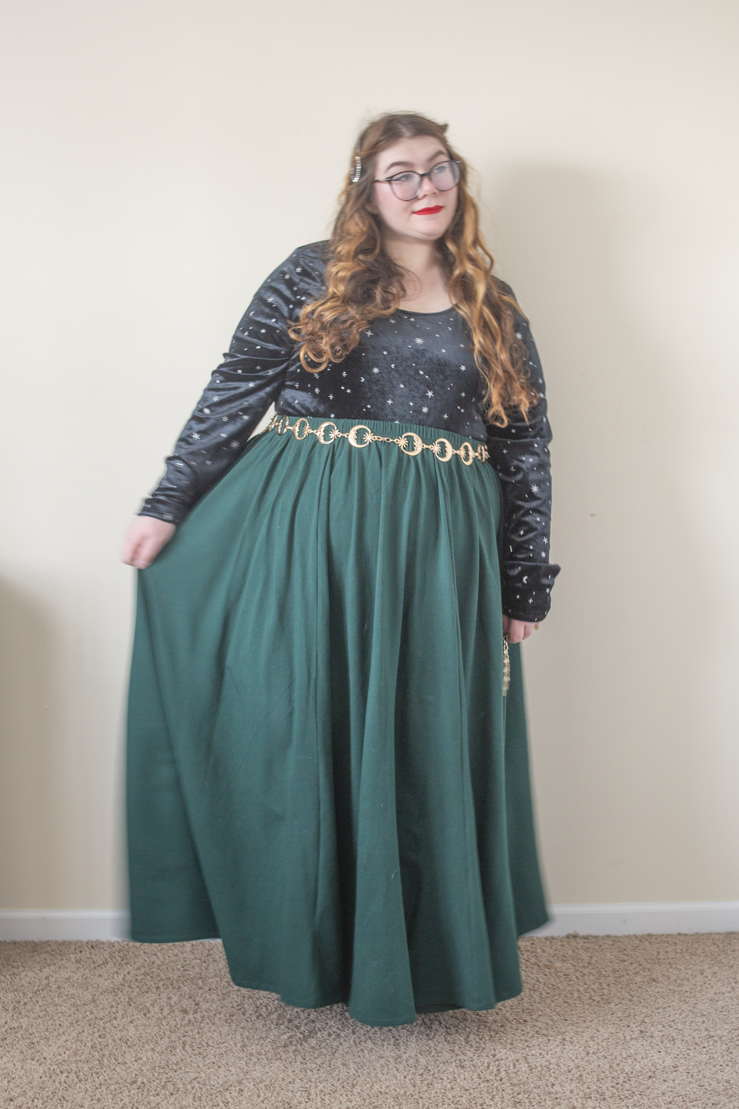 An outfit consisting of a black long sleeve body suit wit silver glitter micro stars and moons tucked into a dark green voluminous jersey maxi skirt and black Chelsea boots.