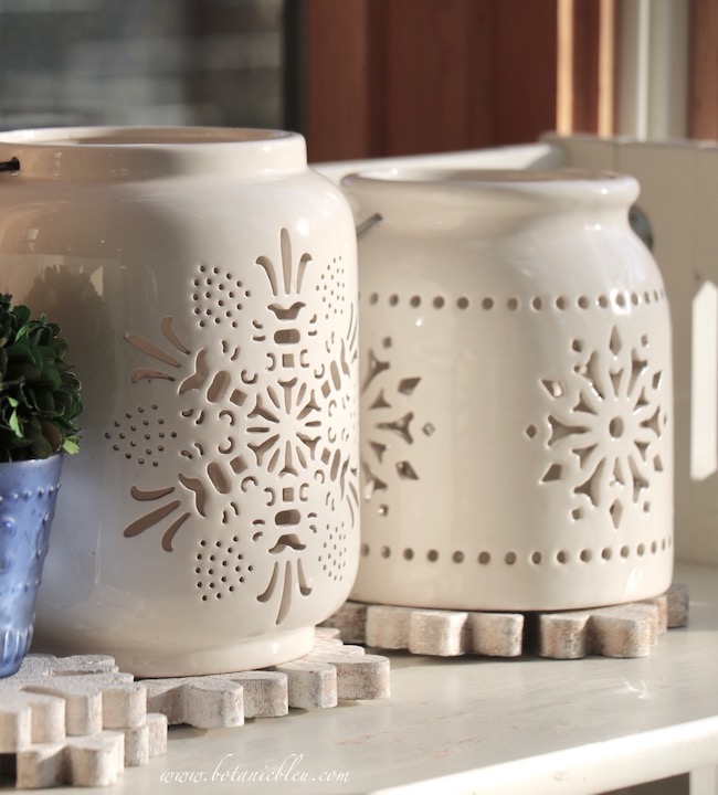 Ceramic snowflake lanterns sit on wooden snowflake ornaments to protect a bookcase from water damage