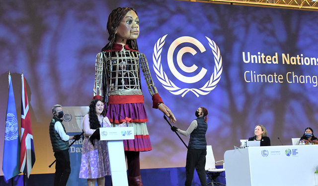 La activista samoana Brianna Fruean comparte protagonismo en la sesión plenaria de la COP26 con Little Amal, una marioneta gigante que representa a una niña refugiada siria.Noticias ONU//Laura Quinones