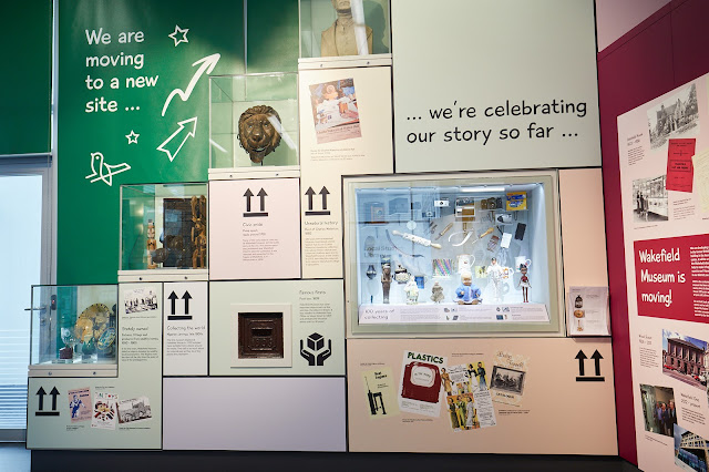 A series of display cases full of assorted objects exploring '100 years of collecting' against a colourful backdrop