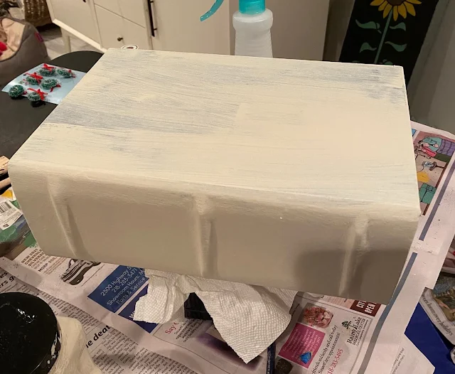 Photo of a hollow book box being painted in off white chalk paint.