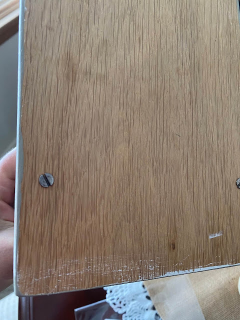 Photo of a cutting board back with two screws driven through it.