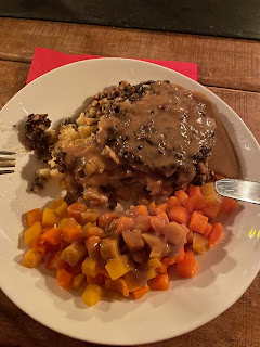 A picture of a plate of food, containing vegetarian haggis over mashed potato, with diced swede and carrot, and cream gravy over the top.