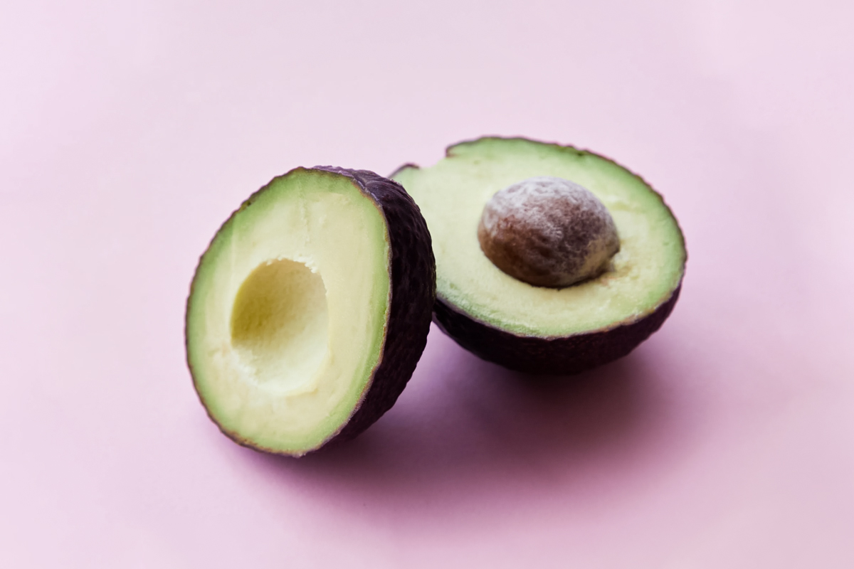 a very beautiful avocado fruit cut in half on pink background