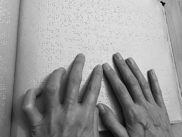 Ruce čtou brailovo písmo v knize
