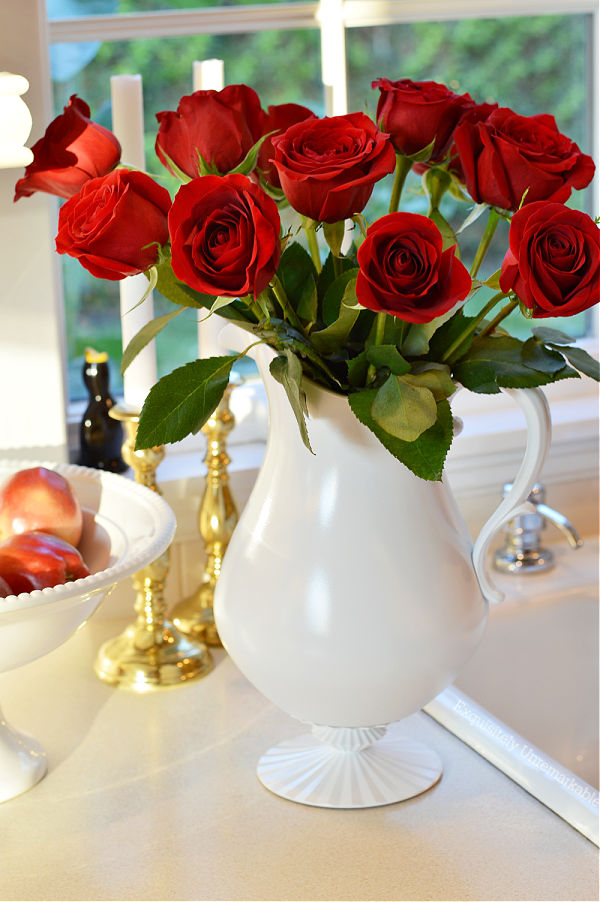 Red roses in white pitcher on counter