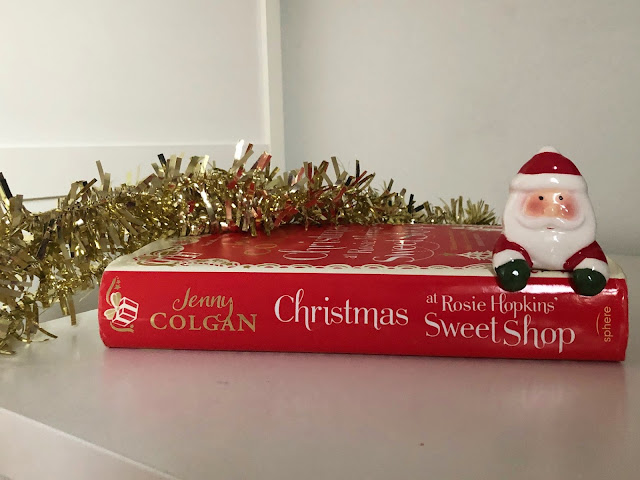 red hard back book spine with small santa head on top and gold tinsel on left