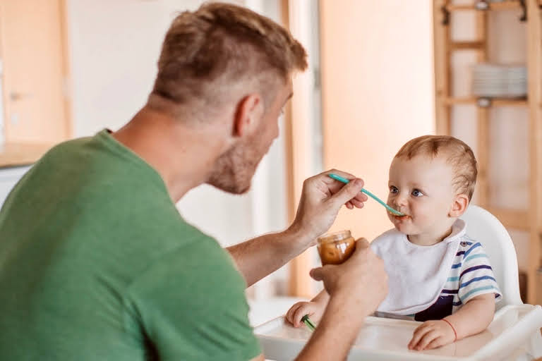 Papá dando de comer un puré a un bebé