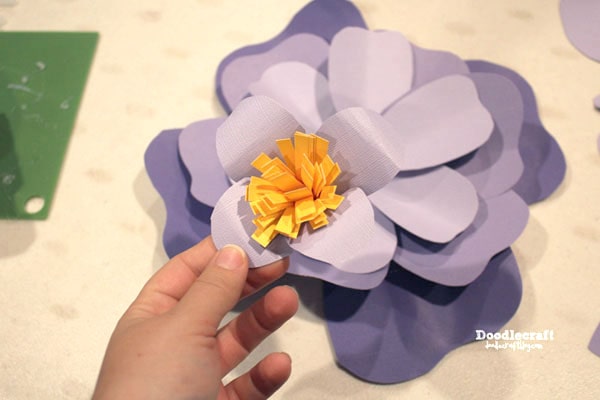 Then glue the 4 final smallest tear-drop shaped petals around the yellow fringe flower center.