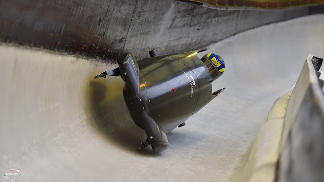 Marina Tuono dentro de um trenó preto, contornando curva em pista de gelo. Se vê apenas a cabeça da atleta que usa um capacete azul e amarelo