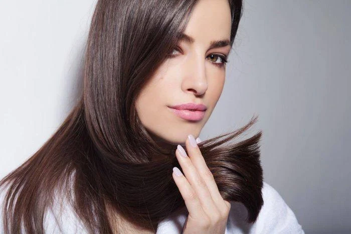 تظهر الصورة فتاة تمسك بشعرها، مما يتيح لنا رؤية جمالية شعرها بعد عملية فرده. تعكس مظهر الشعر الناعم واللامع، مما يدل على نجاح عملية الفرد ورعايته اللاحقة. التركيز في الصورة على كيفية العناية بالشعر بعد الفرد، حيث تبدو الفتاة مطمئنة ومرتاحًة، مما يشجع الآخرين على اتباع نصائح العناية المناسبة للحفاظ على صحة الشعر بعد الفرد. هذه العناية تشمل استخدام المنتجات المرطبة، تجنب المواد الكيميائية القاسية، والاهتمام بالتغذية الصحية لضمان الحصول على شعر جميل وصحي.