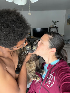 Two people kissing a cat.