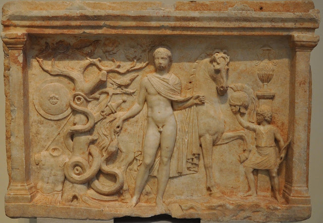 Вотивный рельеф из Аркадии II века н.э. Всадник изображён в героической наготе, его оружие и доспехи развешены на дереве, мальчик-слуга подаёт шлем и держит лук в другой руке. Национальный музей археологии, Афины