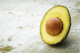 A healthy fruit avocado, which is green in color and it has a brown seed in it. The shown avocado is sliced.