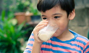 Anak laki-laki sedang minum susu dari gelas