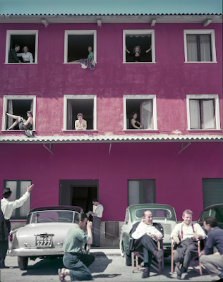 color photo of Extras in windows of building and sitting outside on the set of 8 1/2, Lazio, Italy, 1962