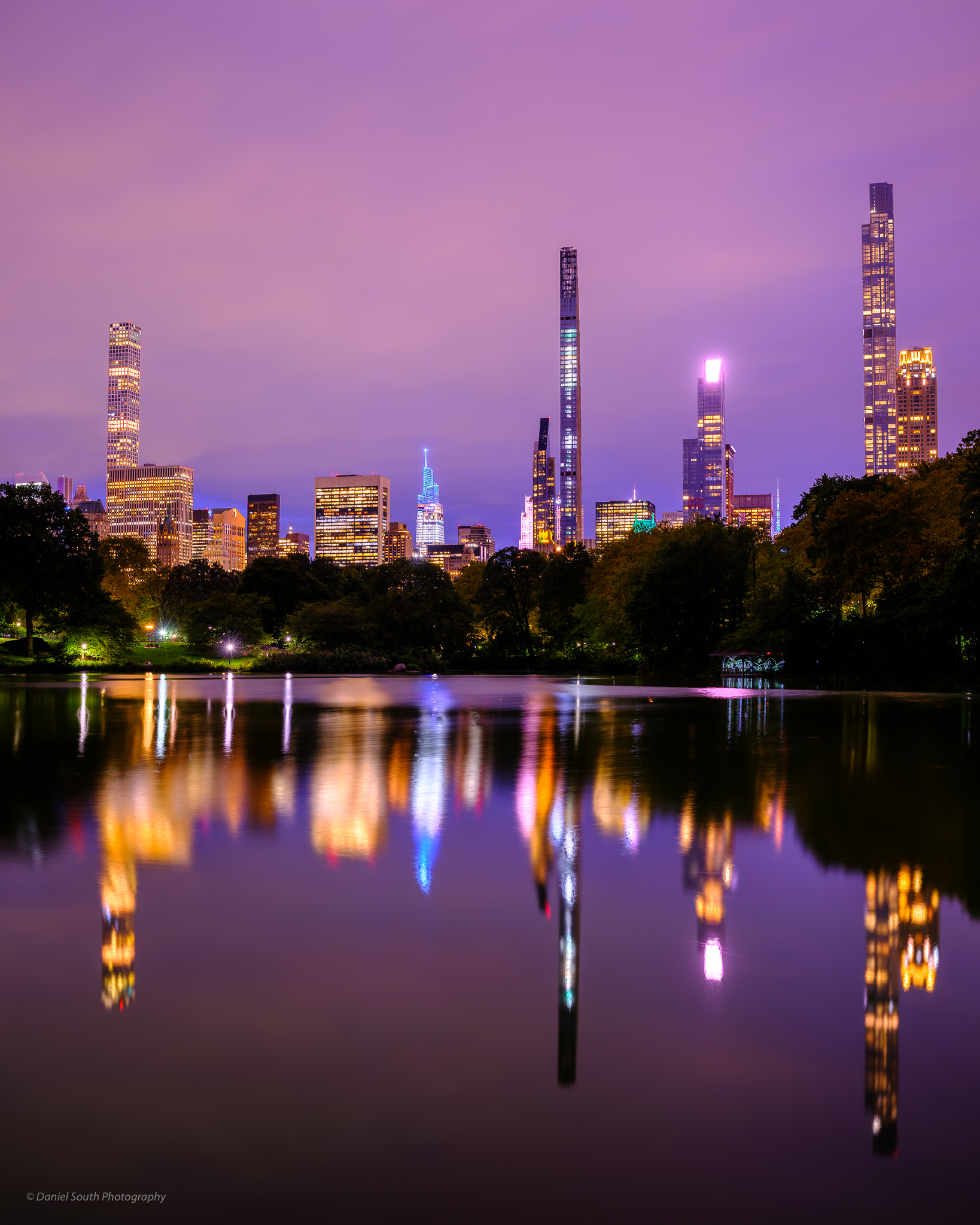 a photo of skyscrapers reflecting in the lake at central park
