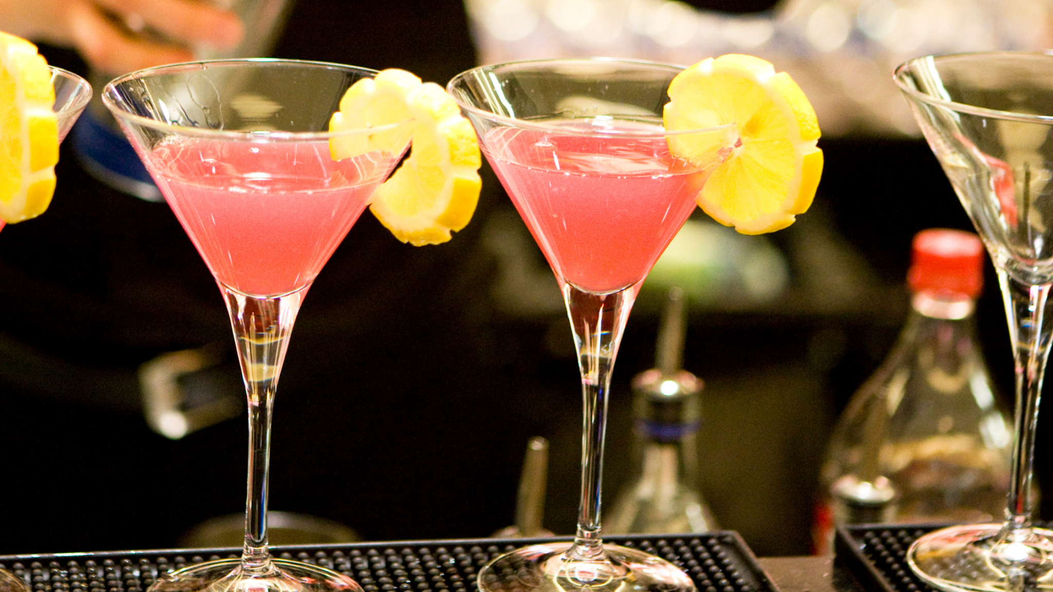 Pink cocktails in martini glasses sit on a counter