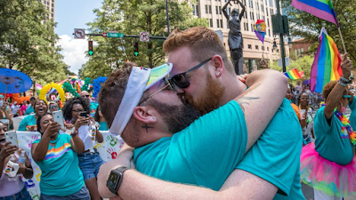 portrait of two men â€” Justin Colasacco and Bren Hipp â€” kissing in celebration just after getting engaged at 2019 Charlotte Pride Festival