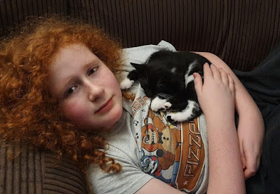 My 13 year old lying on the sofa looking very hot and ill, with a kitten sleeping on his chest