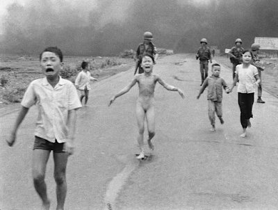 black and white photograph from the Vietnam war of  terrified children, including 9-year-old Kim Phuc, center, as they run down Route 1 near Trang Bang after an aerial napalm attack on suspected Viet Cong hiding places. (AP Photo/Nick Ut, File)