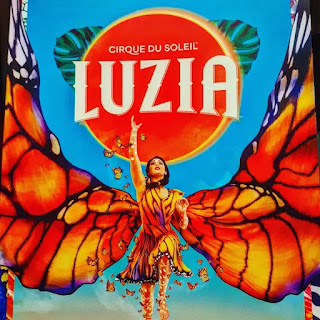 Poster for Cirque de Soleil show Luzia, blue background, woman in monarch butterfly costume in foreground