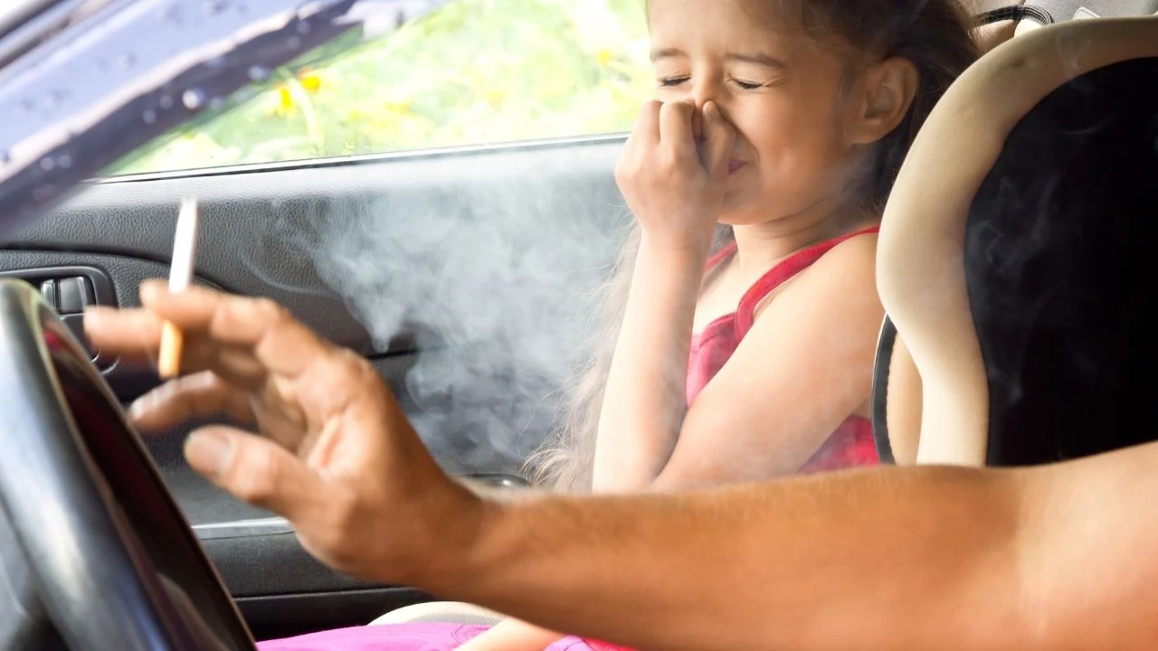 Stop smoking for children. Father smoking cigarette and the hild choking of smoke in a car.