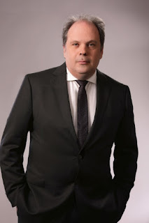 Picture of Shane Neilson wearing a dark gray suit, white shirt, and dark tie