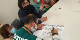 2 personas observando como otra persona pinta un cartel sobre la igualdad salarial