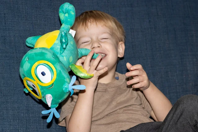 A preschooler throwing a cuddly a toy around while holding it in his teeth