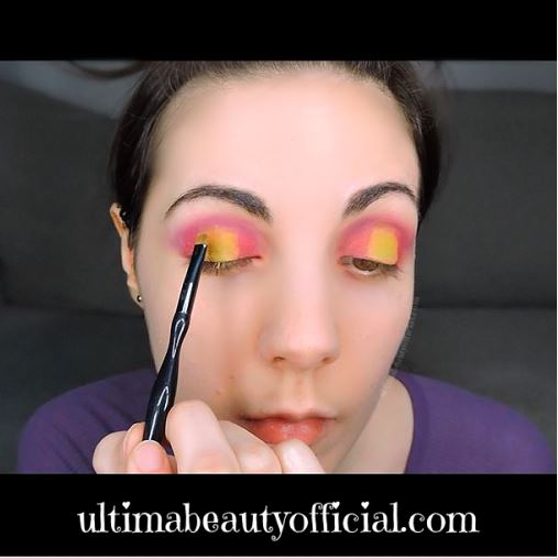 Ultima Beauty applying lime green eyeshadow to the center of the eyelid with a small eyeshadow brush