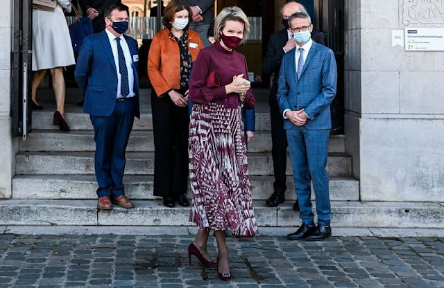 Queen Mathilde wore a wine-red silk top and red printed midi skirt from Natan. Professor Georges Lemaître