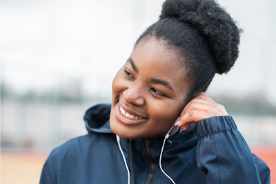 Young woman wearing ear buds listening to a podcast.