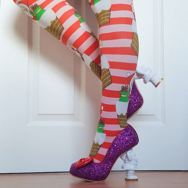 legs in Christmas tights with purple glitter court shoes with red bows and Santa shaped heel