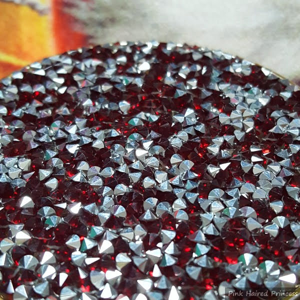 angled surface of compact filled with ruby jewels and silver studs reflecting the light