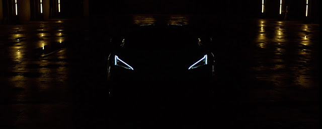 The very first image of revealing of the all-new 2023 Chevrolet Corvette Z06. It's a night and dark scene with some streetlights reflection and the 2023 Corvette Z06 headlights on.