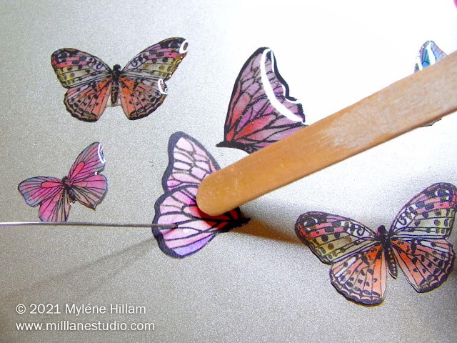 Holding the image still with a pin whilst "painting" the butterfly with resin from the end of a wooden paddle pop stick
