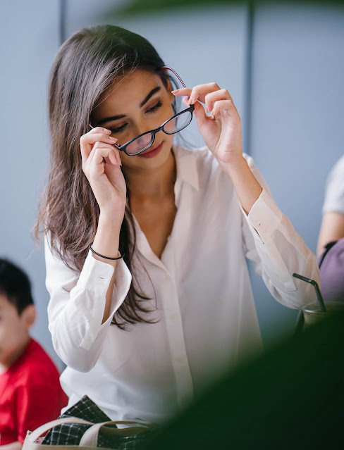 A woman putting on glasses.