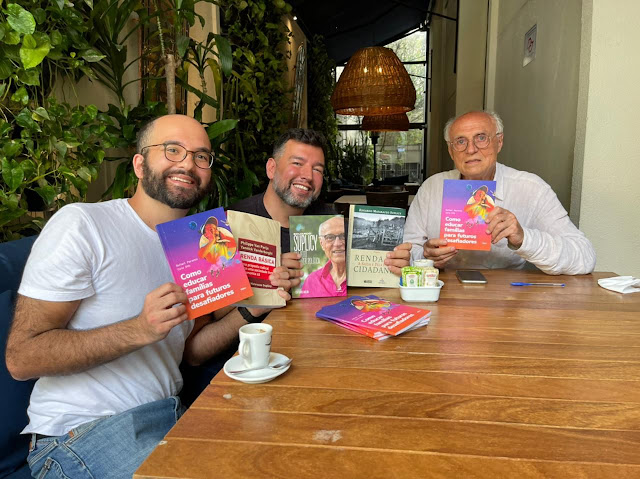 Os educadores autores Caio Dib e Rafael Parente sentados à mesa com o professor e vereador por São Paulo, Eduardo Suplicy.