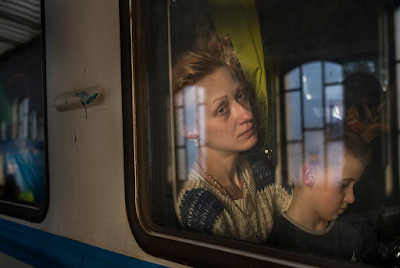 color photograph thrugh train window of mother and child leaving Ukraine