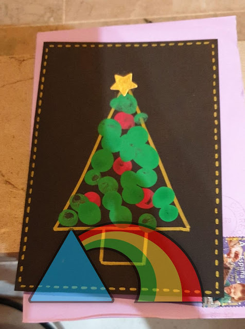 Postal navideña de árbol minimalista hecha con cartulina negra y árbol dibujado con rotulador dorado y pintura de dedos verde y roja