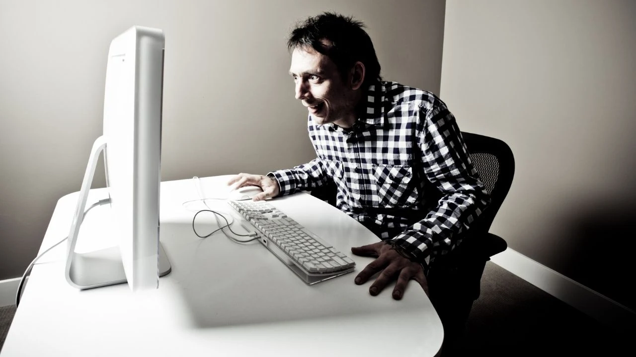 Mid adult man looking at "something" on the computer in his spooky basement.