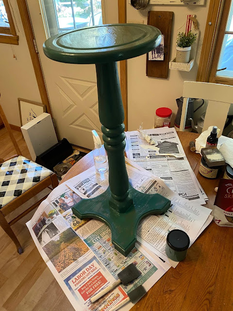 Photo of a pedestal plant stand being painted in Palmetto green from Dixie Belle Paint.