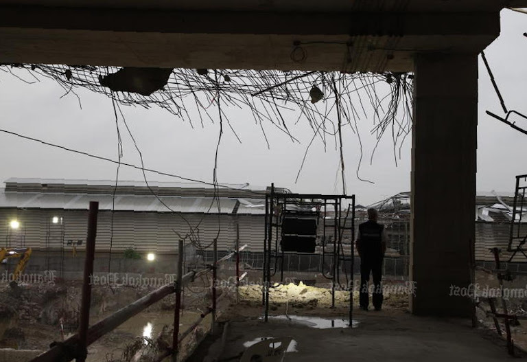 Shadows shroud a construction site as it questions the cost of progress.