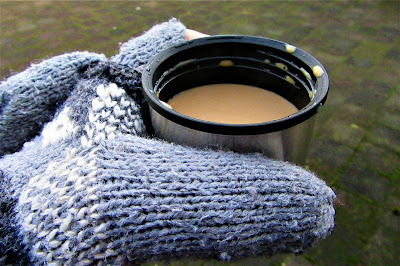 Gloved hands round a mug