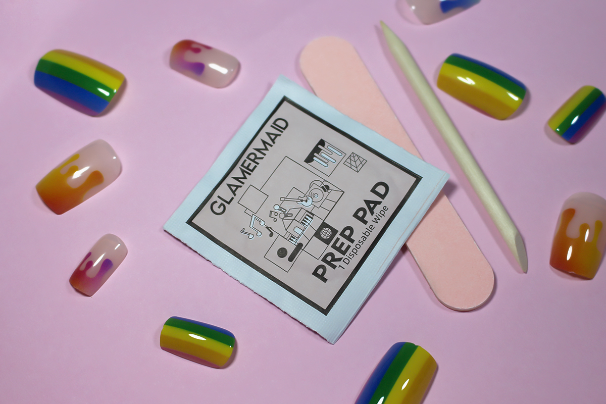 close-up of press-on nails with rainbow design and manicure tools