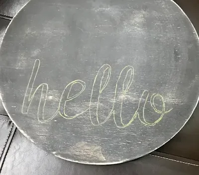 Get the stencil into position, centered in the lower half of the circle, and lightly draw on the hello with a colored pencil.