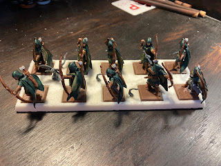 Ten cloaked archers standing in a line, five by two, on top of a white plastic tray.